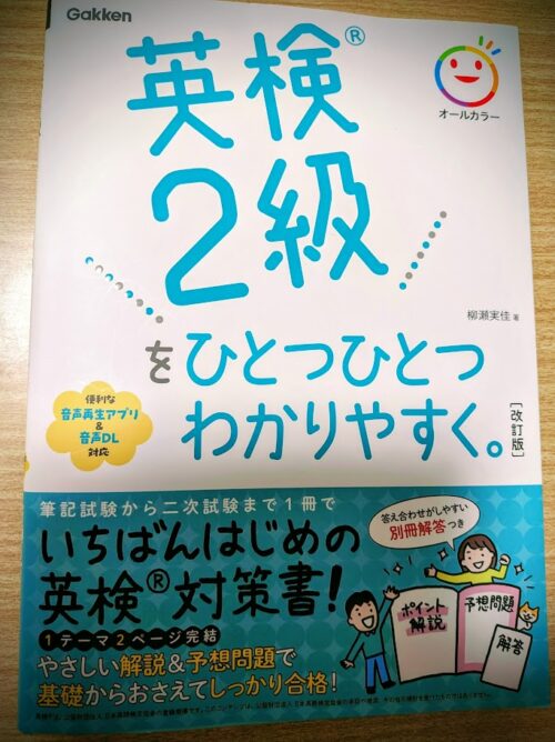 学研プラス発行の書籍「英検2級 をひとつひとつわかりやすく。」[改訂版] の表紙画像。オールカラーで親しみやすいイラストが描かれている。