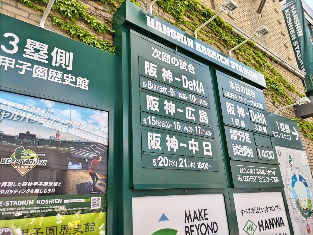 阪神甲子園球場の外壁にある試合日程表と、ツタが絡まる伝統的な球場の外観。