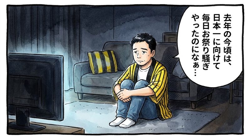 少し明かりを落としたリビングで、テレビ画面を見つめながら膝を抱えてポツンと座り、「去年の今頃は、日本一に向けて毎日お祭り騒ぎやったのになぁ…」と寂しそうにしている黄色と黒の法被姿のお父ちゃんを描いた一コマ漫画。ミディアムショットの構図。16:9。
